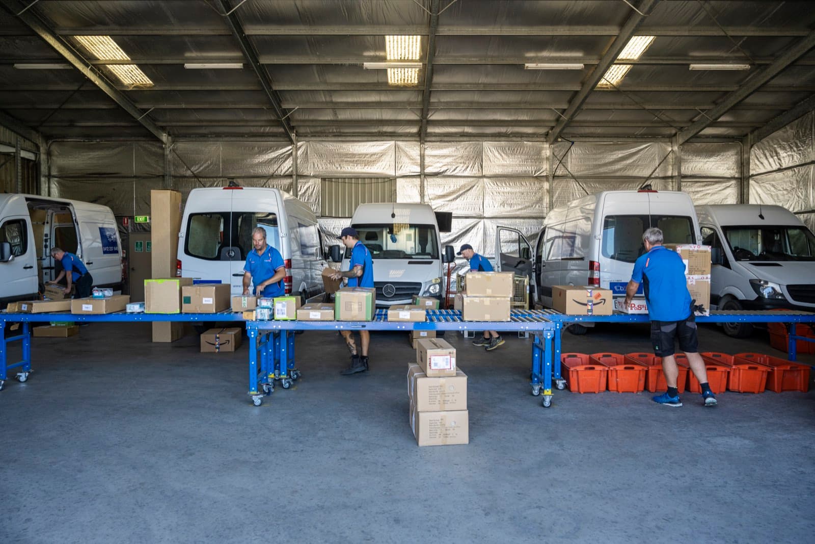 The Fleurieu Logistics team loading freight beside the Sprinter van fleet in the McLaren Vale depot